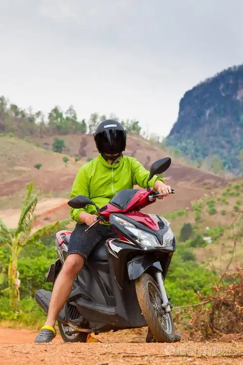 坐在摩托车上的年轻人.自行车在山上路过的路上.在丛林中旅行.