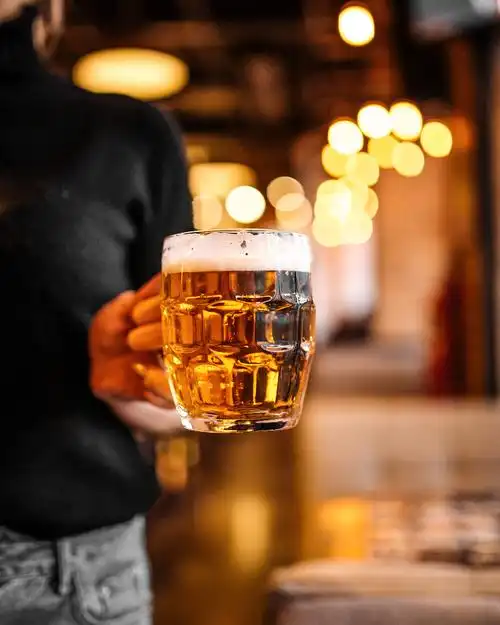 模糊背景中一个女人手里端着一杯啤酒