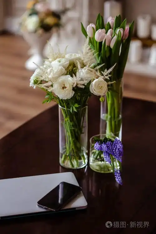 一束花,放在一张靠近手机和笔记本电脑的桌子上,放在优雅的简单花瓶里