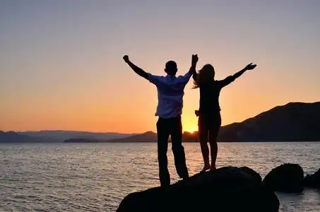 一个女孩跟一个男人举起双手向太阳照片