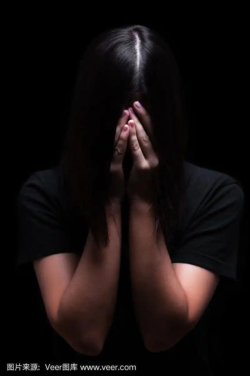 情绪化的女人哭着用手捂着脸掩盖泪水,在一个黑色或黑色的背景上.