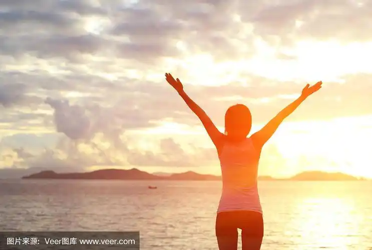 欢呼的女人张开双臂迎接日出的海边