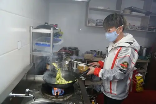 图为陆海华正在厨房炒菜