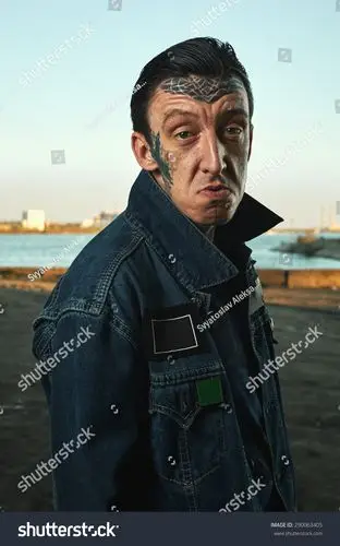 流氓与纹身在牛仔夹克在街头做鬼脸-人物,美容/时装服饰-海洛创意