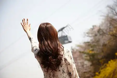 户外伸手感受阳光的女性背影图片素材