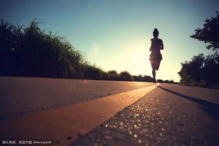 一个健身的女人早上在海边的小路上跑步