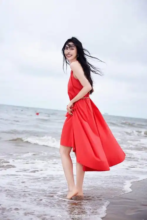 张俪穿红色长裙赤脚漫步海边 海风吹动长发回眸氛围感拉满