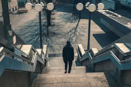 环境楼梯一个穿着黑衣服的年轻人在荒凉的环境中走下楼梯照片