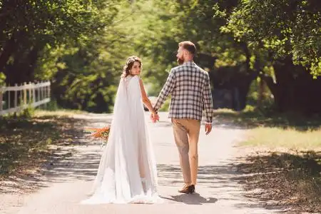 幸福生活背影婚礼当天,新娘和新郎手牵着手走在花园里.