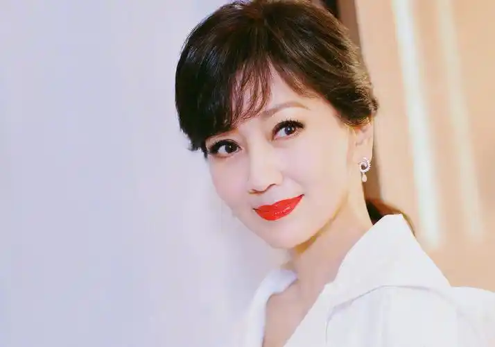 照片中的赵雅芝身穿一身白衣,腰间系有蓝色腰带,涂上红唇格外显气 ..