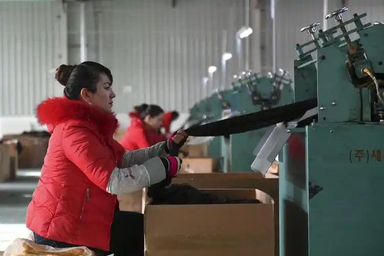 在新疆和田洛浦县浩林发饰生产车间内,一名女工使用机器拉制发丝(11月