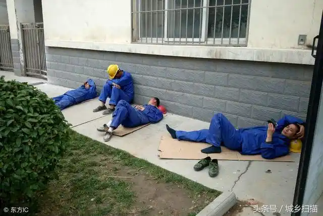 工地上,中午13时许,四名穿着统一服装的农民工在屋檐下垫着纸箱板睡觉