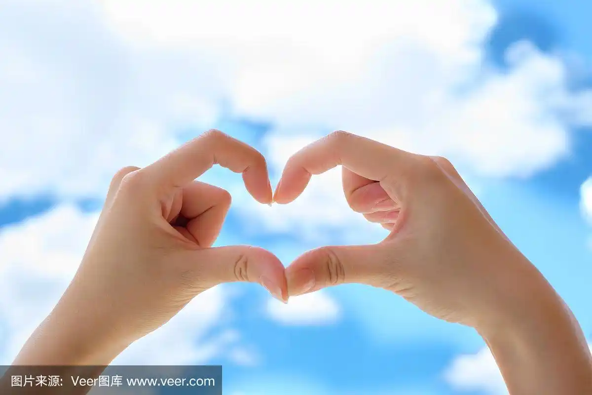 以蓝天为背景的女人双手制作心形