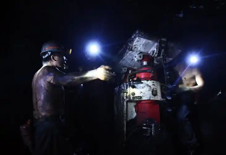 几名矿工正在挪动综采支架,综采支架在工作面对矿工安全起到很大的