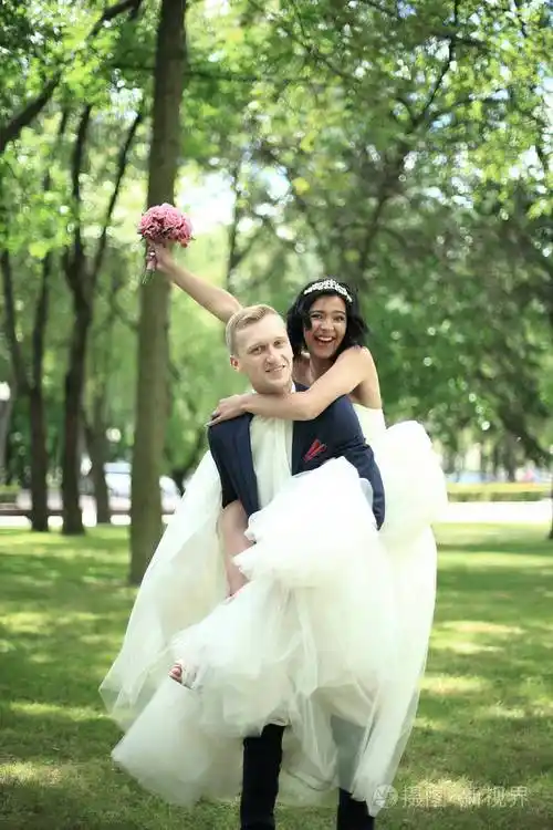 幸福的新郎抱在怀里的他的新娘