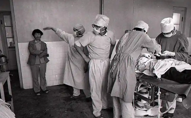 图中是90年代中期的医院中,几位医生正在给一名青年男性做结扎手术.