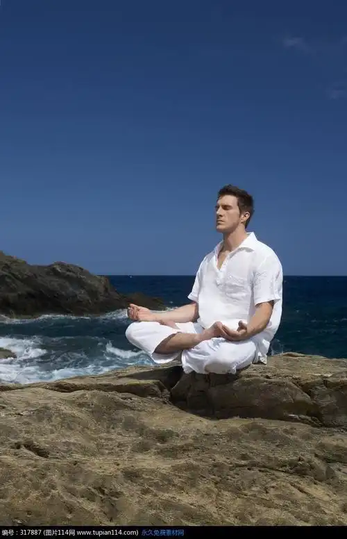 海边石头上盘腿坐着的外国男人