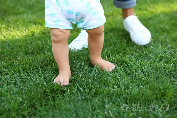 可爱的小宝宝在户外的绿草上学走路特写