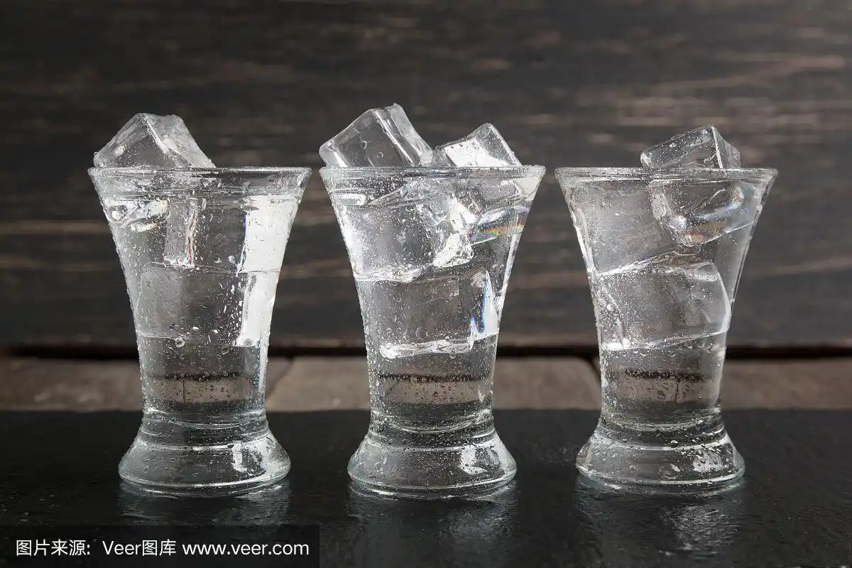 深色木桌上放着加冰的俄罗斯伏特加酒杯