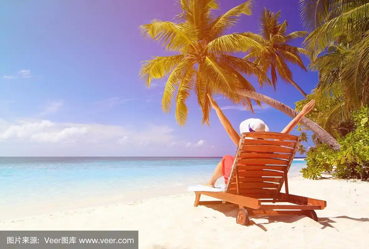 快乐的女人坐在热带海滩的沙滩椅上