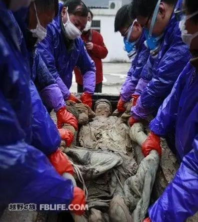 工作人员将明代不腐女尸抬出棺外