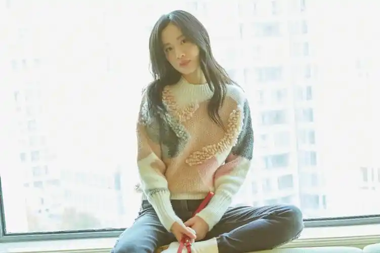 照片中,李梦置身于室内,身穿粉色拼接毛衣搭配修身牛仔裤,休闲舒适又