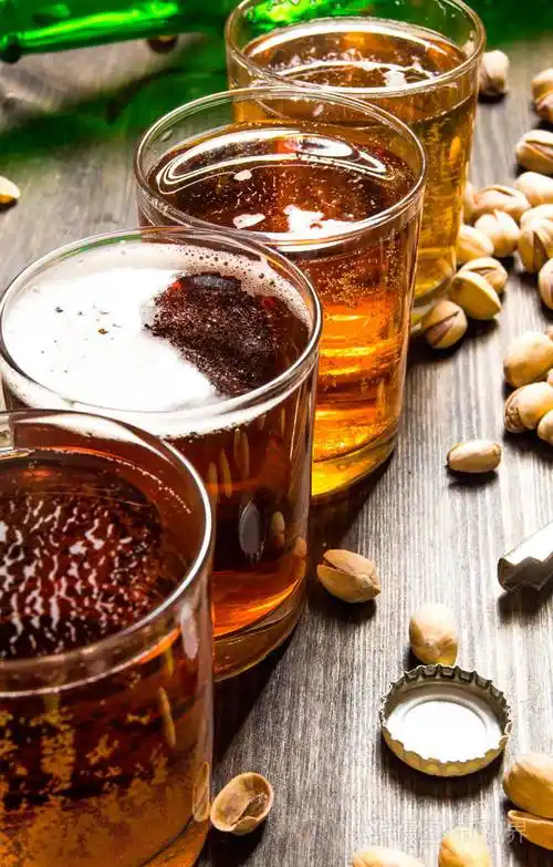 四个啤酒用木制的桌子上的开心果