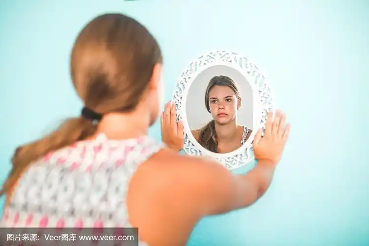 悲伤的女孩对着镜子哭泣