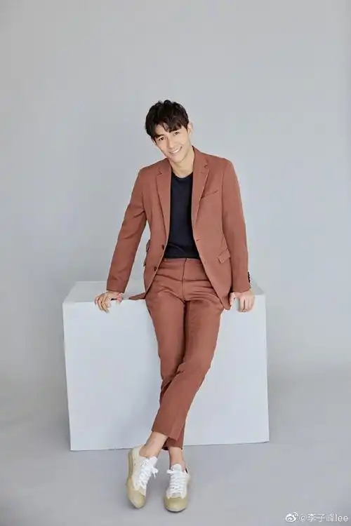 照片中的李子峰还是一头微长的头发,身穿暗橘色西服套装,好身材和大
