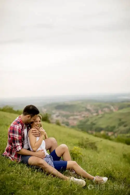 爱的情侣坐在山上的草地上拥抱着