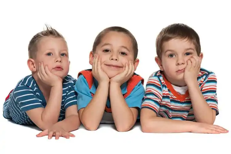 三个小小的朋友,三个小男孩在一起躺在白色的背景