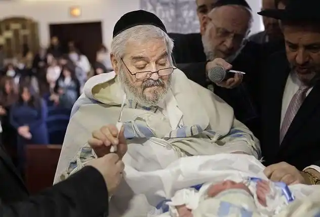 上图:一位纽约的犹太拉比正在给婴儿行割礼.