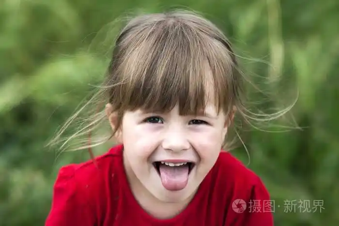 微笑的小女孩显示的舌头.年轻可爱的小女孩 gesturi