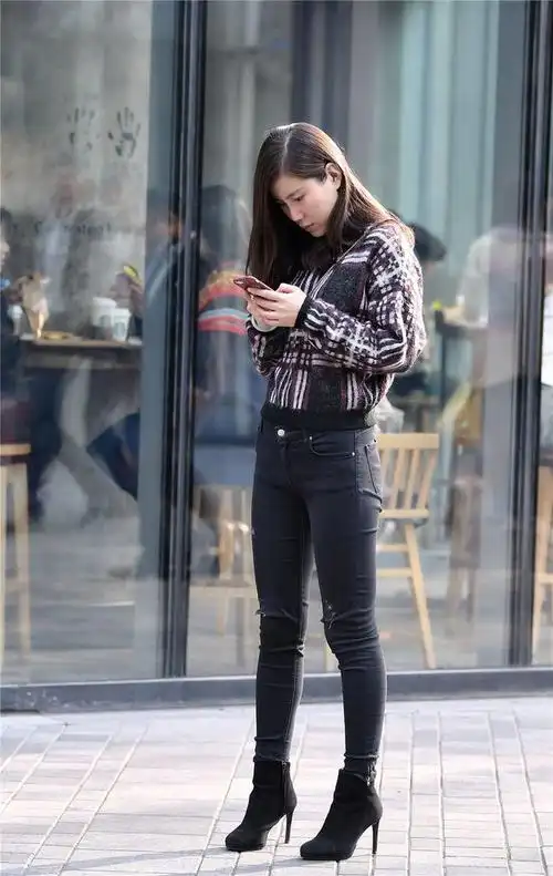 黑色紧身牛仔裤搭配黑色细高跟短靴穿出时尚风格