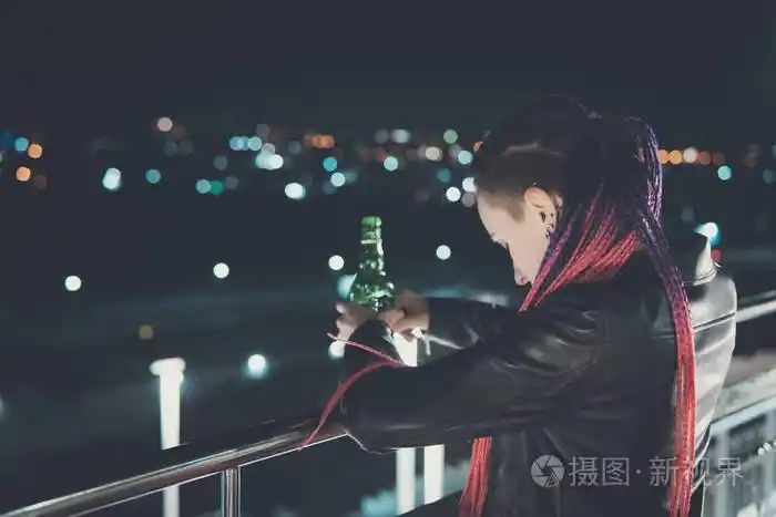 醉酒的女孩在城市的背景下, 晚上在高高的地板上往下看.