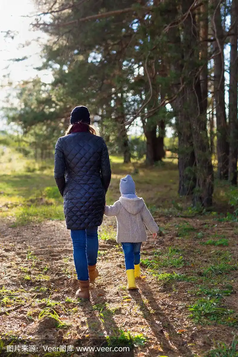 妈妈牵着孩子的手一起走在森林里