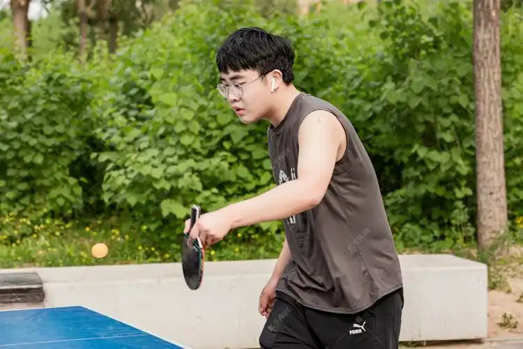 运动白天打球的男生户外打乒乓球摄影图配图