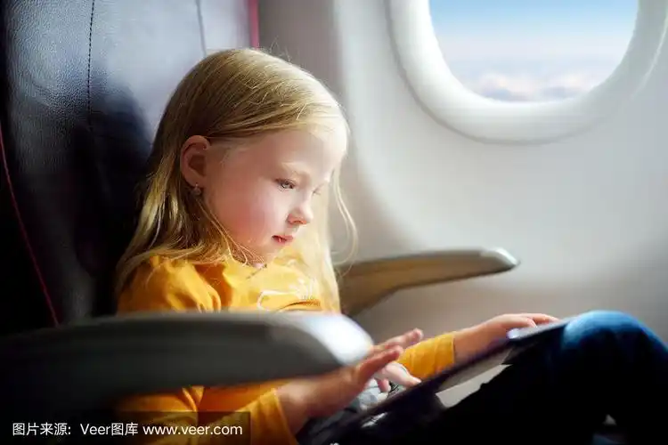 儿童坐在飞机窗口,使用数字平板电脑