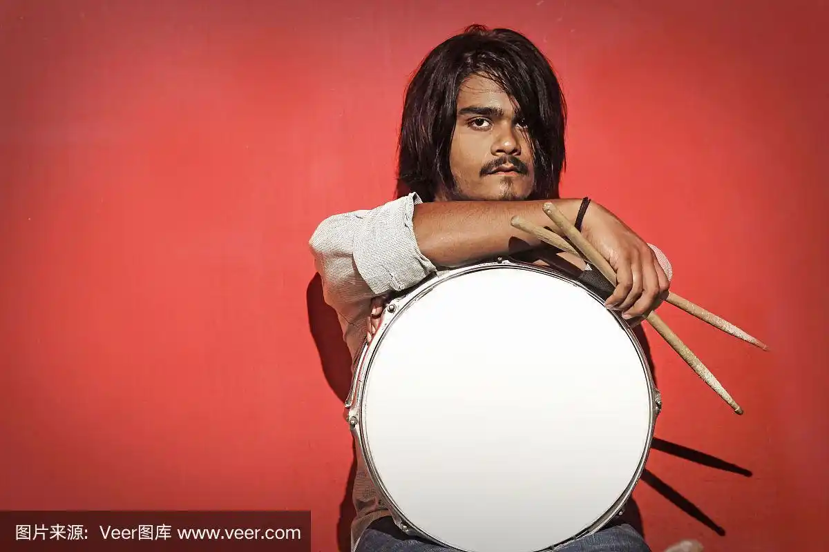 年轻的鼓手拿着棍棒和军鼓孤立在红色背景上