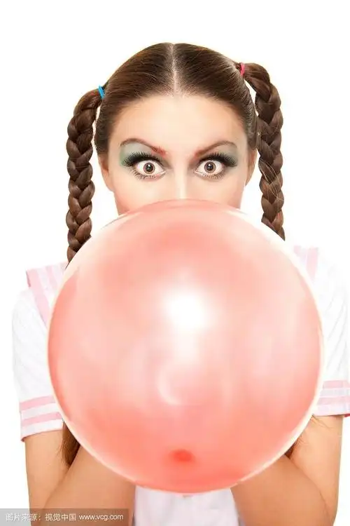 迷人的年轻女子吹红气球