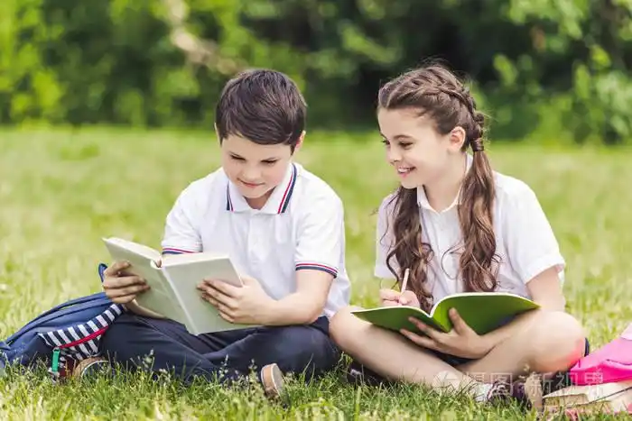 可爱的小学生一起做作业, 坐在公园的草地上照片-正版商用图片0uk1wz