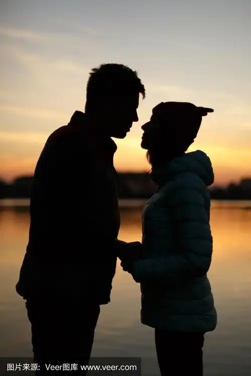 湖边夕阳下一对情侣的剪影.sun between people profiles.