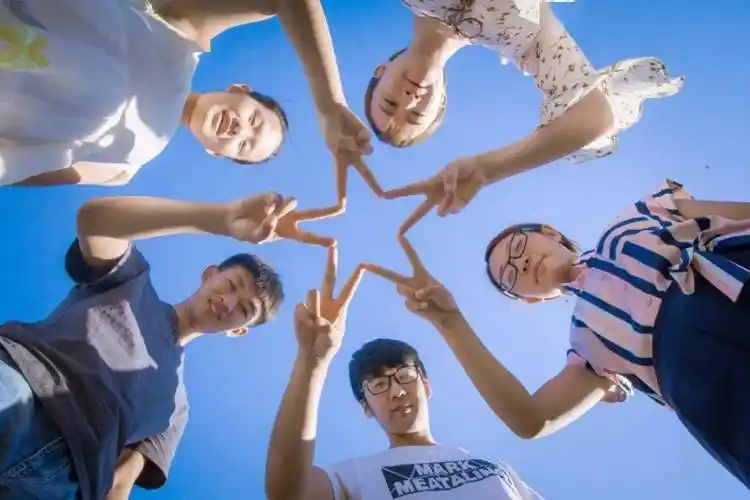 大家围成一圈向下看,手指比耶围成一个圈,摄影师躺中间向上仰拍,创意