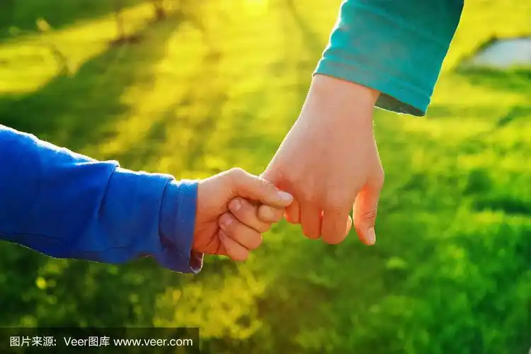 母亲和儿子在日落时牵着手,养育孩子