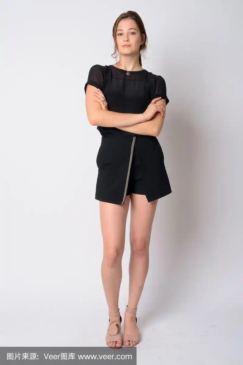 年轻美丽的女人双臂交叉的全身照片