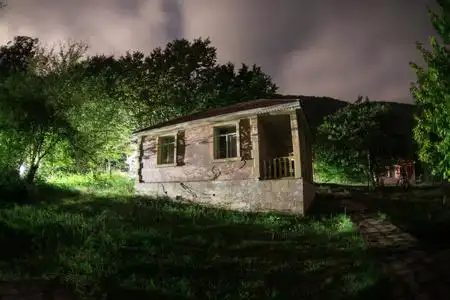 晚上在森林里建筑的山夜风景与月亮或老式乡下房子在晚上与云彩和星.