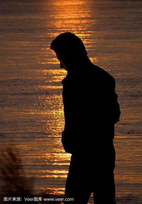 日落时,海边一个孤独的人的剪影