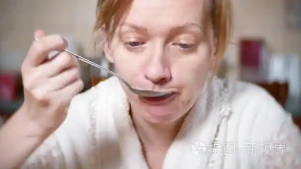 穿着睡衣的脸色苍白的女人正在餐桌上吃饭她累了4k背景模糊特写