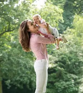 妈妈和宝宝在冬季公园母亲母乳喂养婴儿在公园长椅上快乐妈妈和宝宝坐