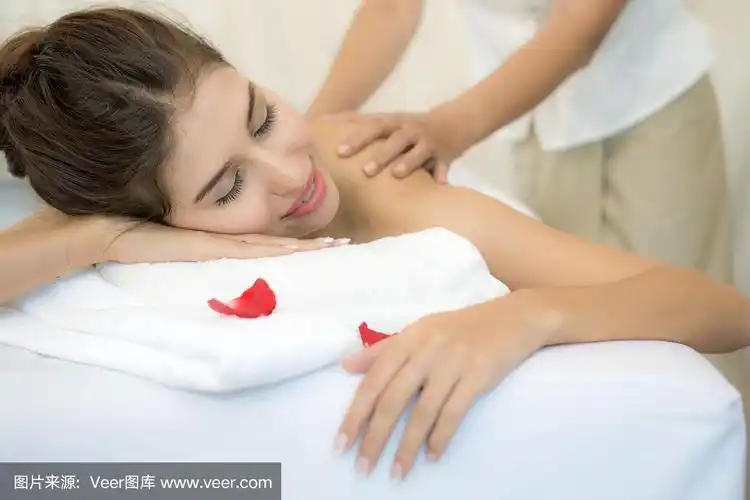 美丽和健康的年轻女子放松与背部按摩水疗沙龙